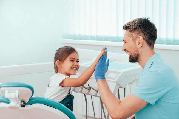 Child and dentist high fiving because of good children's oral health